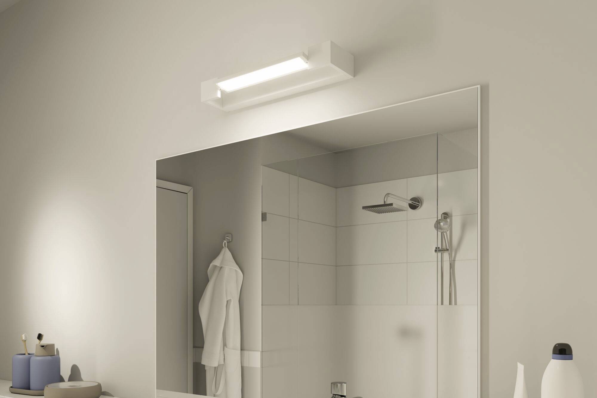Une salle de bain avec un grand miroir au mur. En dessous, un espace lavabo avec un gobelet à brosse à dents et une serviette à gauche.