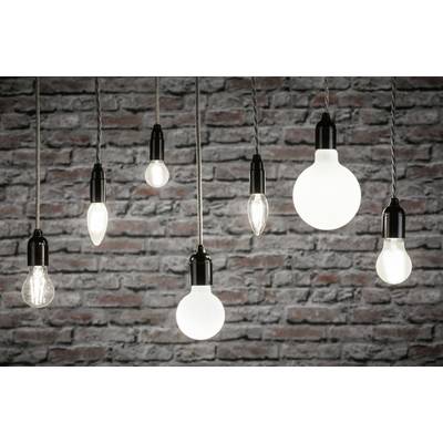 Plusieurs ampoules suspendues devant un mur de briques brillent avec des intensités différentes, créant une atmosphère industrielle.