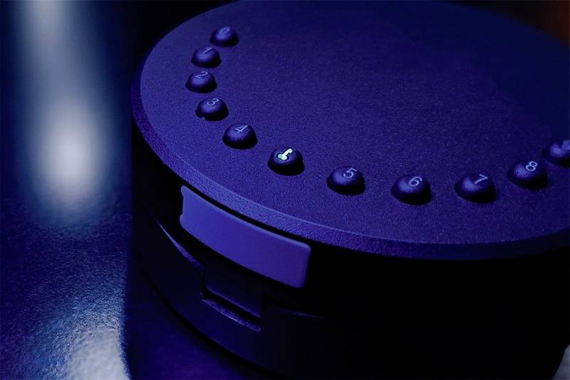 Un appareil illuminé en bleu avec des touches numérotées disposées en cercle, la touche '5' étant mise en valeur. Environnement sombre et futuriste.