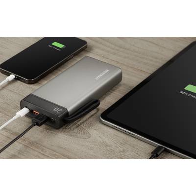 Un smartphone, une batterie externe et une tablette sont posés côte à côte sur une table. Le smartphone et la tablette sont en cours de chargement.