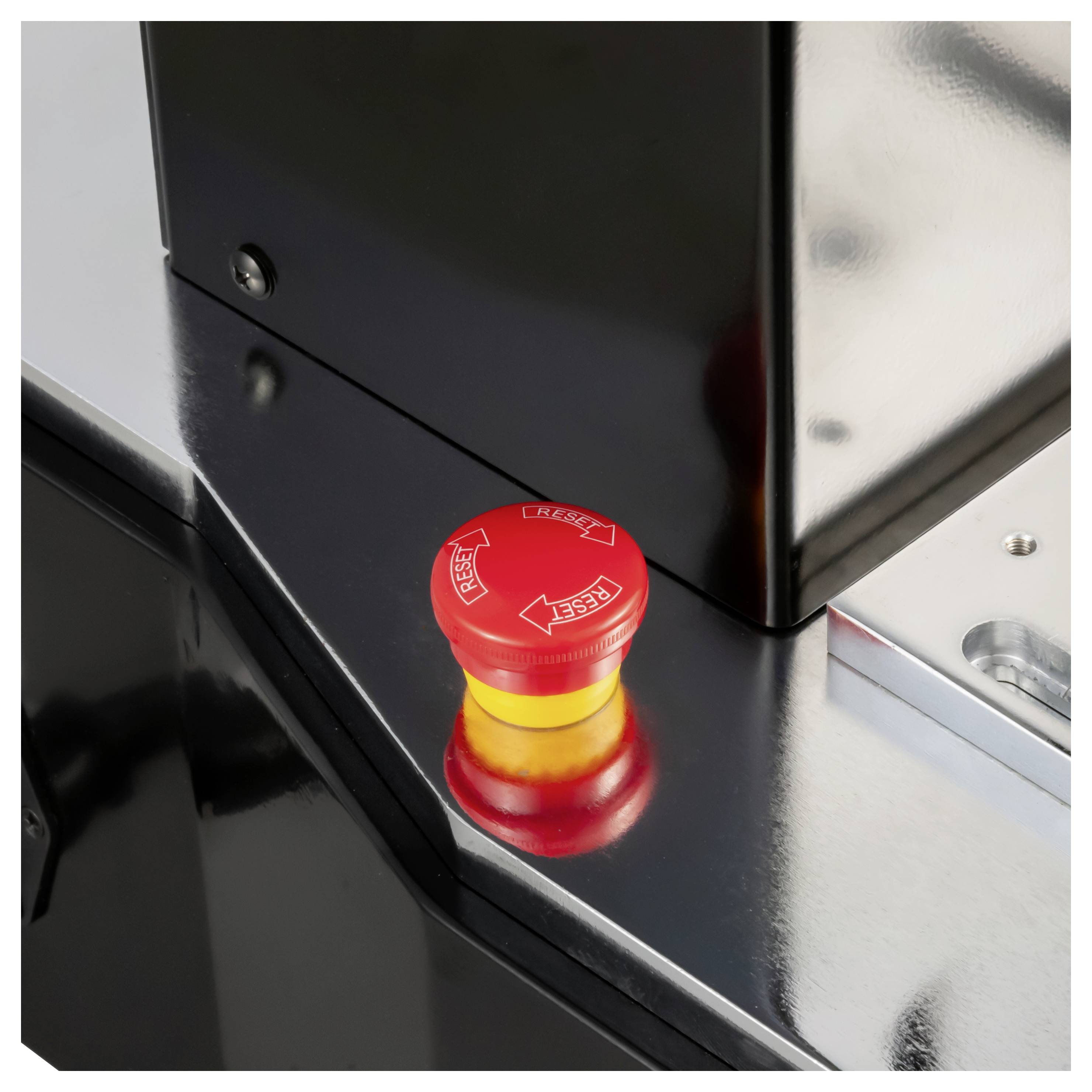 Bouton d'arrêt d'urgence rouge sur un panneau de machine noir, utilisé pour arrêter rapidement l'équipement en cas d'urgence.