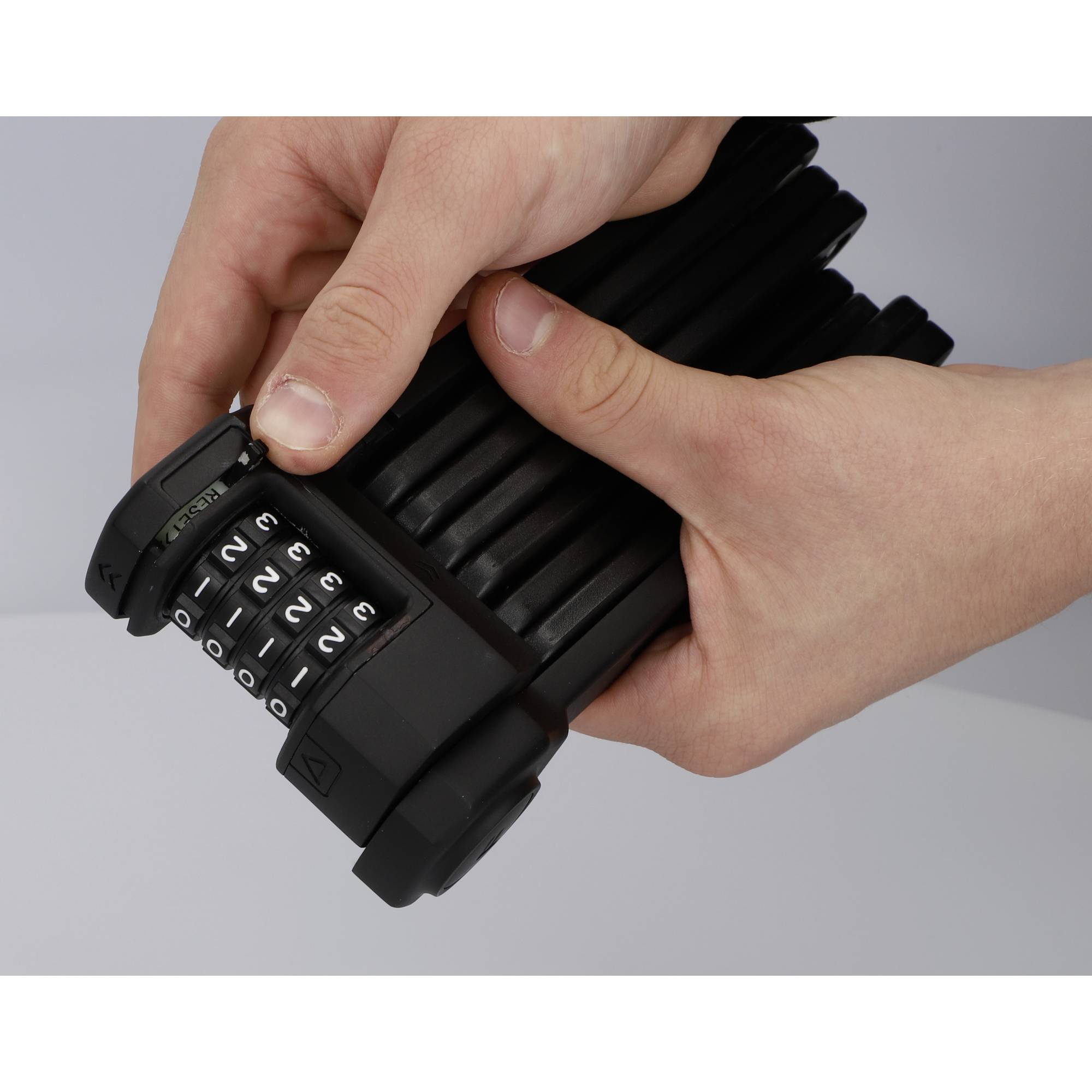 Deux mains tiennent un cadenas noir pliable avec un code numérique. La combinaison de chiffres est partiellement visible.