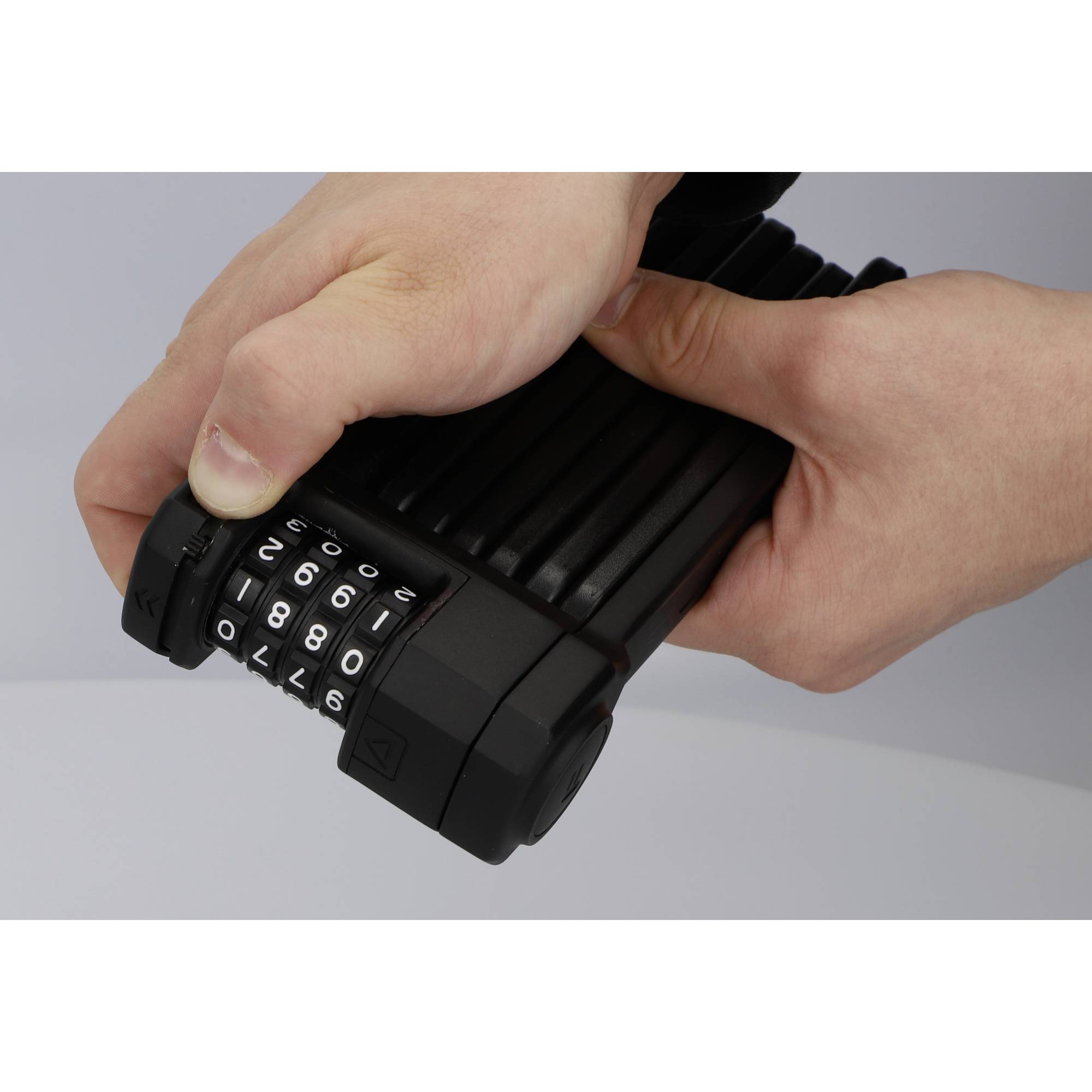 Une personne tient un cadenas à code avec les chiffres 1800 sur un cadenas de vélo noir.