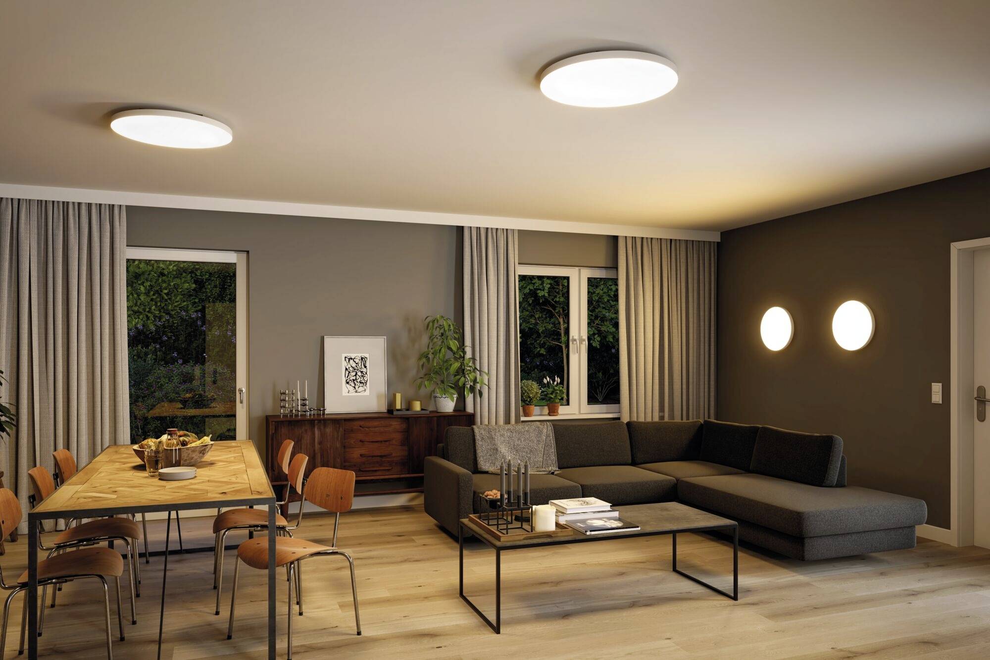 Salon moderne avec sol en bois, canapé gris, table à manger et chaises, et plantes. Éclairage élégant et décoration murale.