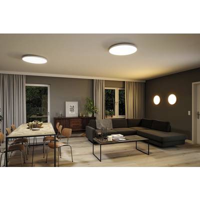 Un salon moderne avec un canapé, une table à manger et des chaises. Deux luminaires au plafond éclairent la pièce, décorée dans des tons chaleureux.