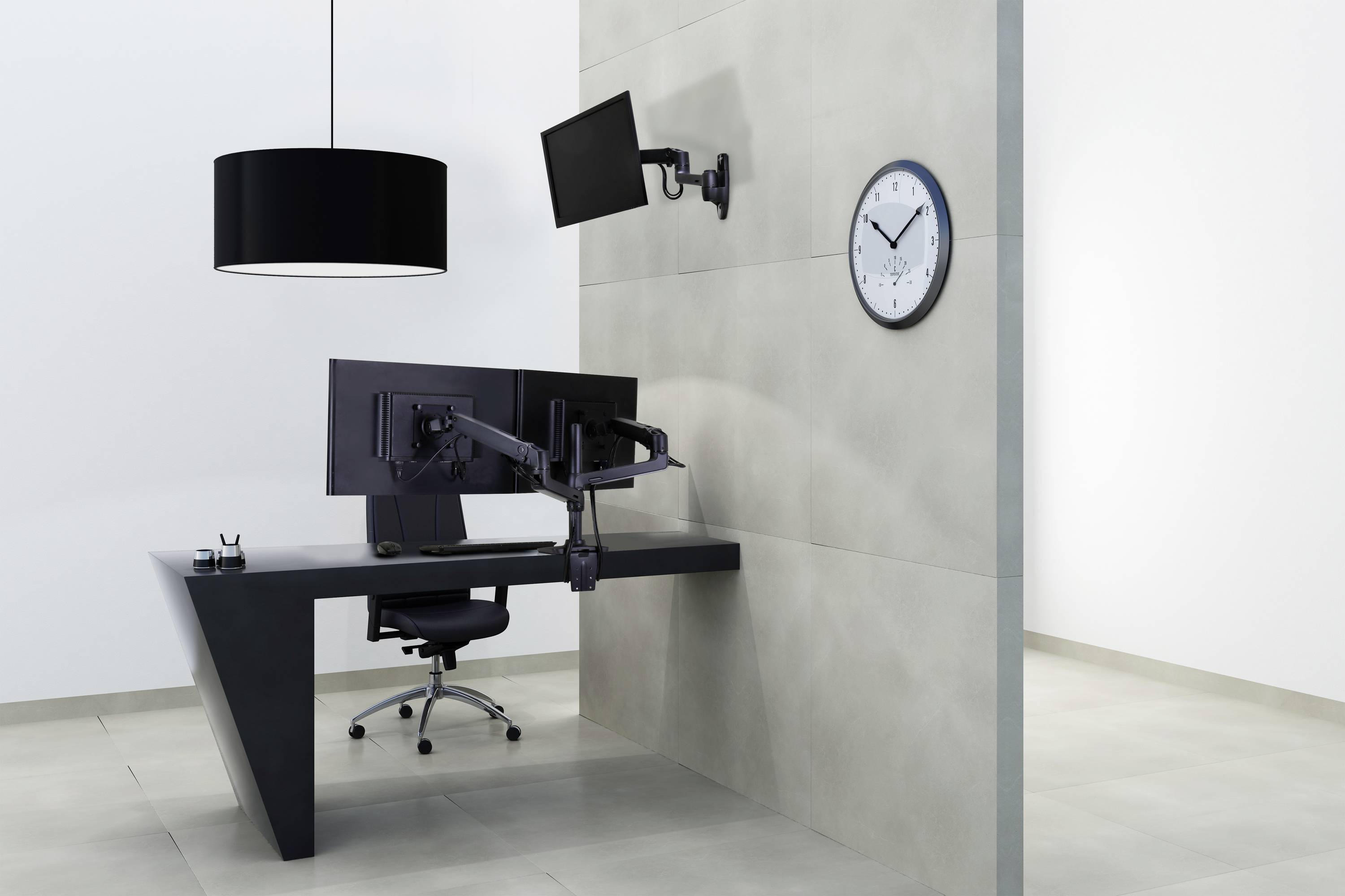 Bureau moderne avec un bureau sombre, deux écrans, une chaise noire et une lampadaire. L'horloge au mur indique 10h10.