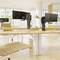 Bureau avec des bureaux modernes, des supports de moniteurs, des chaises vides et de grandes fenêtres laissant entrer beaucoup de lumière du jour.
