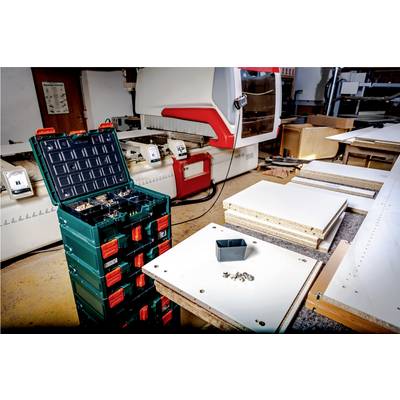 Un atelier moderne de travail du bois. Au premier plan, une boîte à outils verte. Différentes planches de bois sur l'établi.