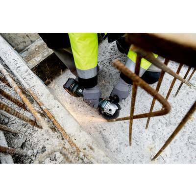 Un ouvrier, vêtu d'un équipement de protection, coupe un morceau de métal avec une meuleuse d'angle sur un chantier. Des étincelles volent.
