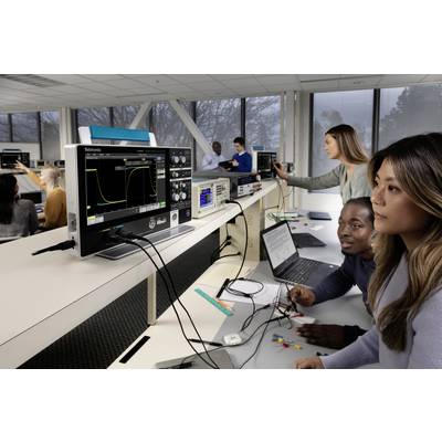 Des étudiants travaillent dans un laboratoire avec des oscilloscopes et des ordinateurs portables sur un projet électronique, entourés d'équipements techniques et d'écrans.