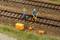 Scène de train miniature avec deux personnages vêtus de tenues de travail sur des rails, utilisant des outils de voie ferrée. Entourés de petites boîtes à outils.