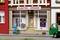 Un modèle miniature d'un magasin d'électricité avec l'enseigne 'ÉLECTRO - BÖRNER'. Une personne se tient devant, une voiture verte est à droite.