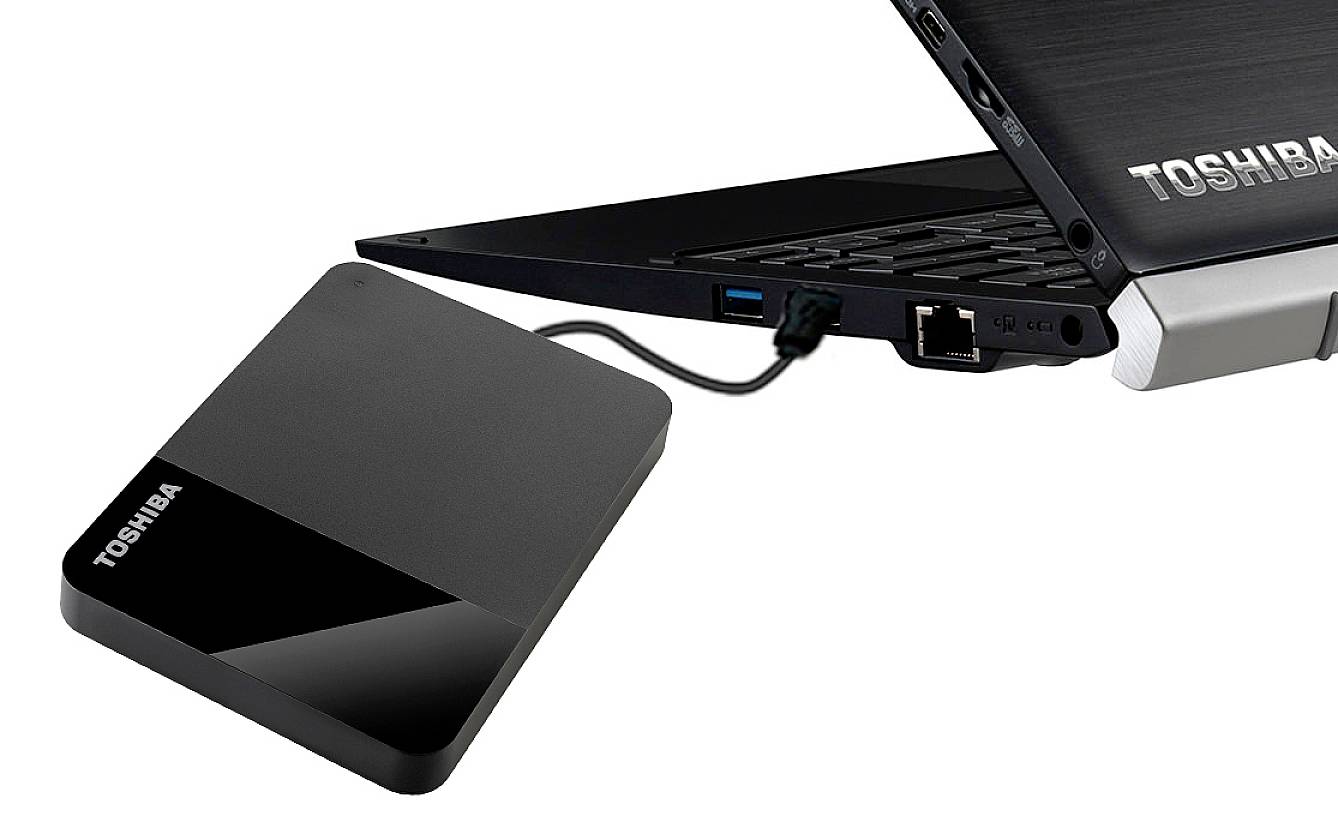 Disque dur externe Toshiba connecté à un ordinateur portable via un câble USB, l'ordinateur étant représenté dans sa position ouverte.