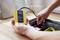 Une personne teste une prise électrique à l'aide d'un appareil de mesure jaune Wiha pour vérifier la tension.