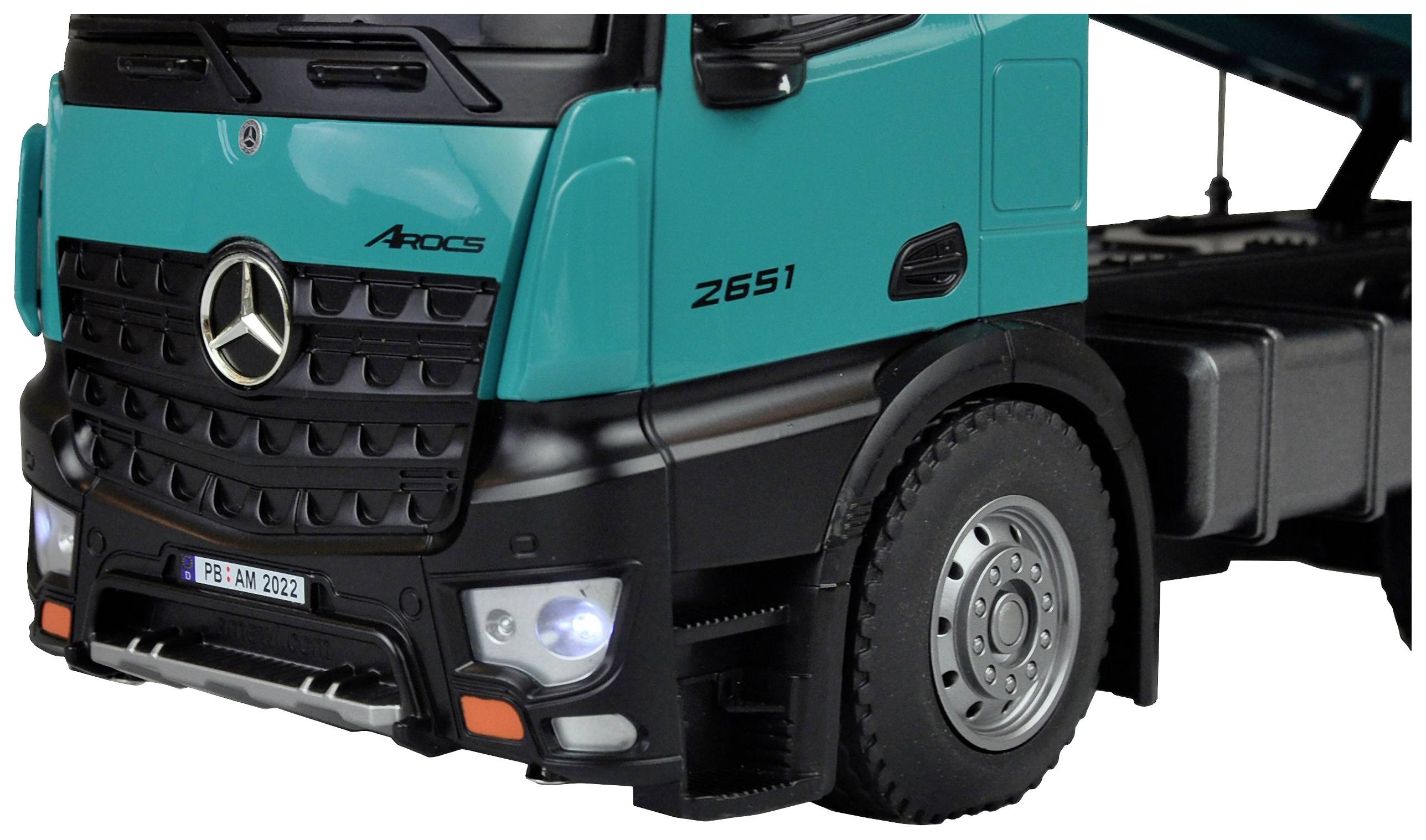 Le gros plan montre l'avant d'un camion vert avec un emblème, des phares et des parties des roues.