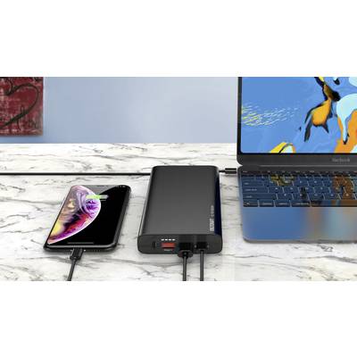 Un smartphone et un ordinateur portable se chargent simultanément avec une batterie externe sur une table en marbre. L'écran du smartphone affiche l'état de la charge.