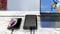 Un smartphone et un ordinateur portable se chargent simultanément avec une batterie externe sur une table en marbre. L'écran du smartphone affiche l'état de la charge.