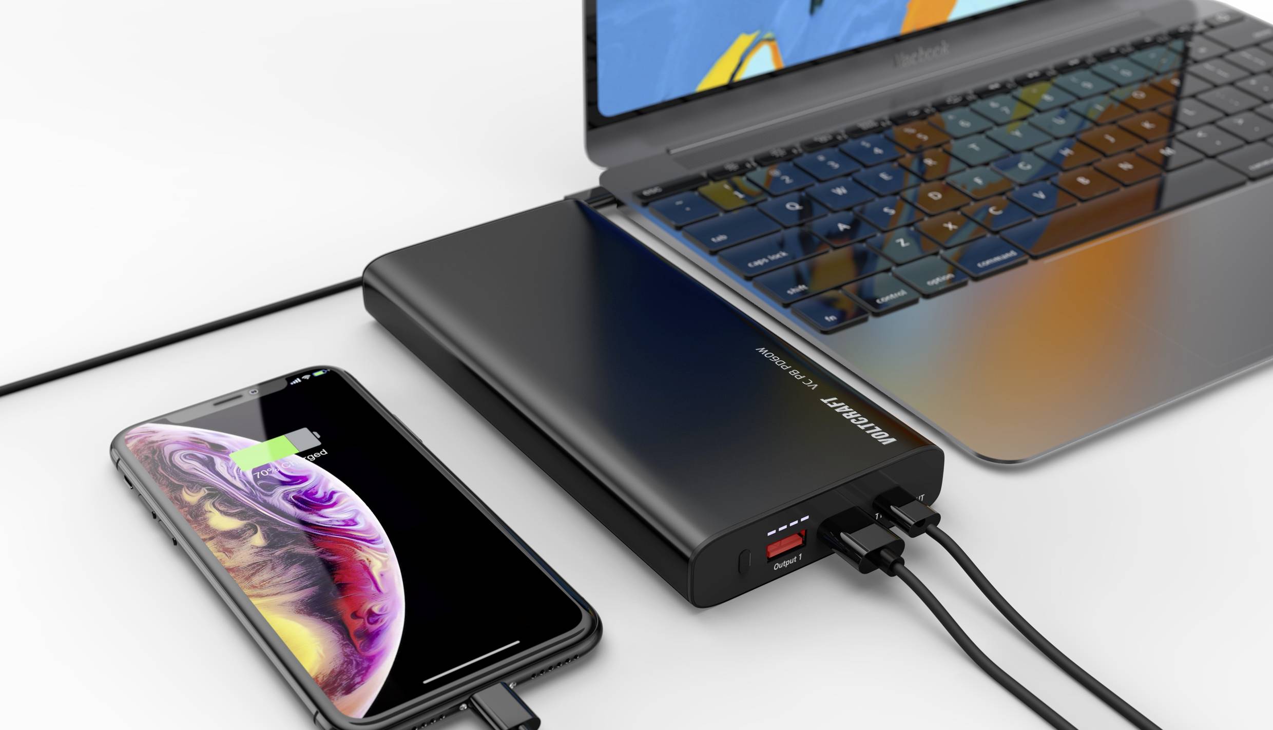 Un ordinateur portable et un smartphone sont chargés simultanément par une batterie externe. L'état de charge du smartphone est affiché.