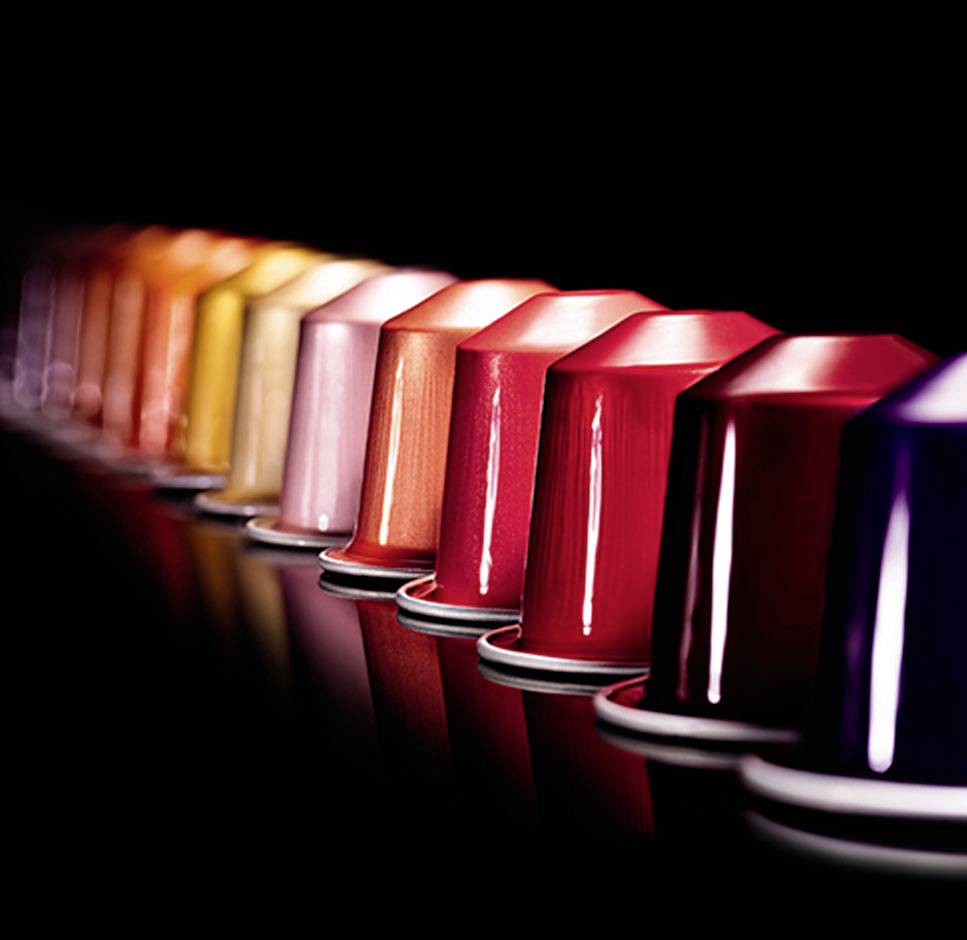 Une rangée de capsules de café colorées dans différentes nuances et couleurs, s'étendant de gauche à droite.