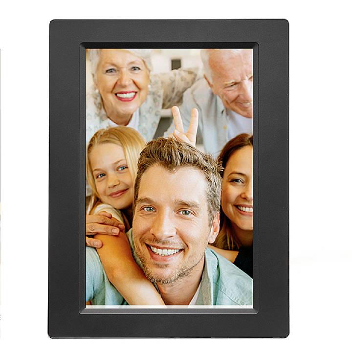 Une famille joyeuse de trois générations sourit pour une photo. Les grands-parents sont en arrière-plan, les parents et l'enfant au premier plan.