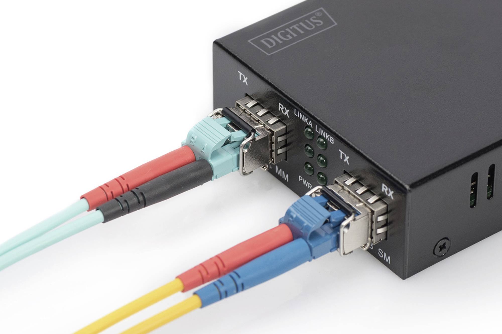 Convertisseur média noir avec câbles à fibre optique connectés. Quatre voyants LED indiquent l'état de fonctionnement.