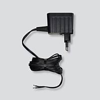 Un adaptateur secteur noir avec câble et fiche européenne pour recharger des appareils électroniques, sur un fond gris.