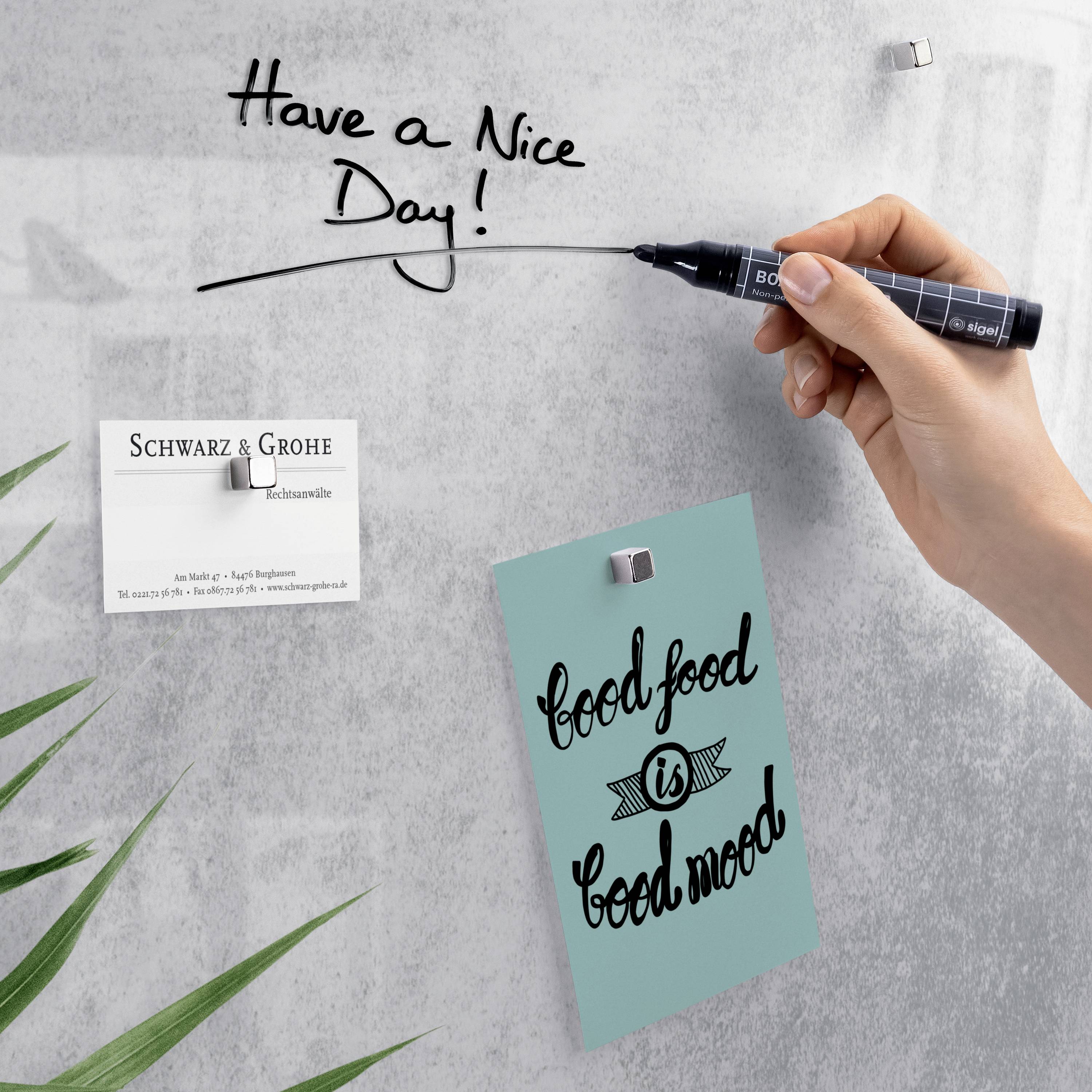 Une main écrit 'Have a Nice Day!' sur un tableau blanc. Une note indique 'good food is good mood', à côté d'une carte de visite de 'Schwarz & Grohe'.