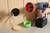 Une personne fore un trou rond dans un mur en bois à l'aide d'une perceuse. Un boîtier d'installation vert et des câbles sont visibles.