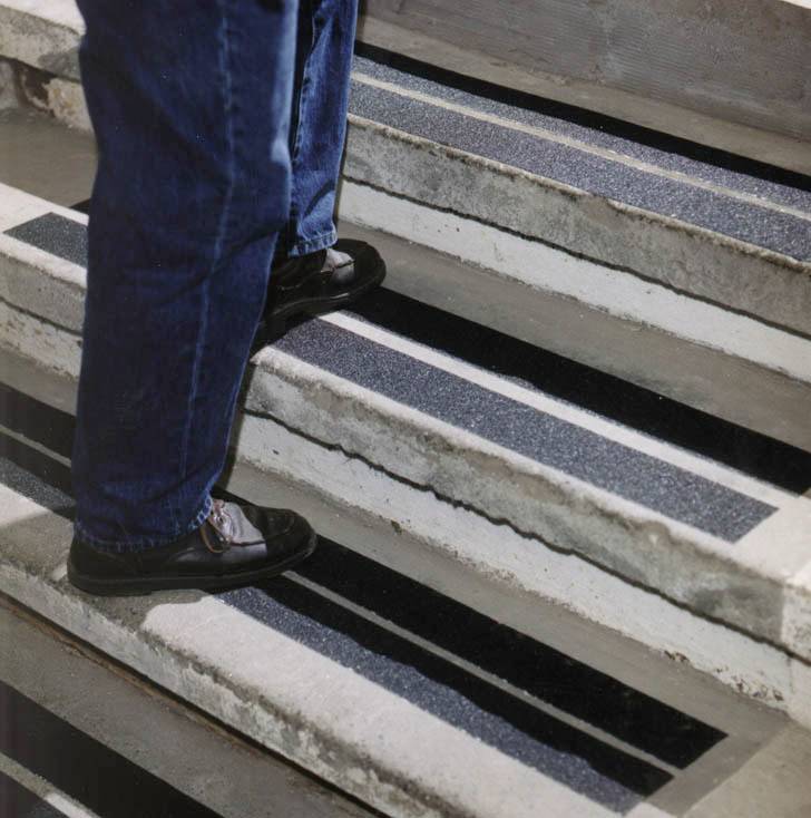 Une personne monte un escalier muni de bandes antidérapantes sur les marches afin d'améliorer la sécurité.