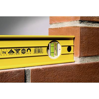 Un niveau jaune est posé sur une arrête maçonnée, indiquant un plan parfaitement horizontal ; un symbole de précision dans le domaine de la construction.
