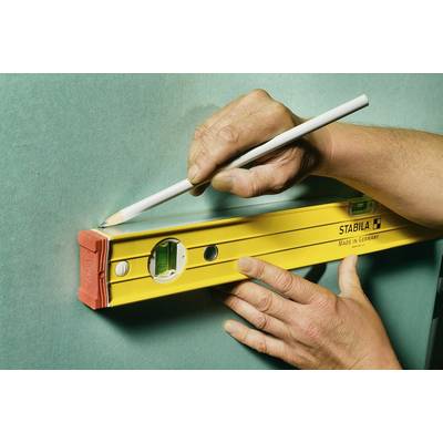 Une personne utilise un niveau jaune et un crayon pour marquer une ligne droite sur un mur vert.
