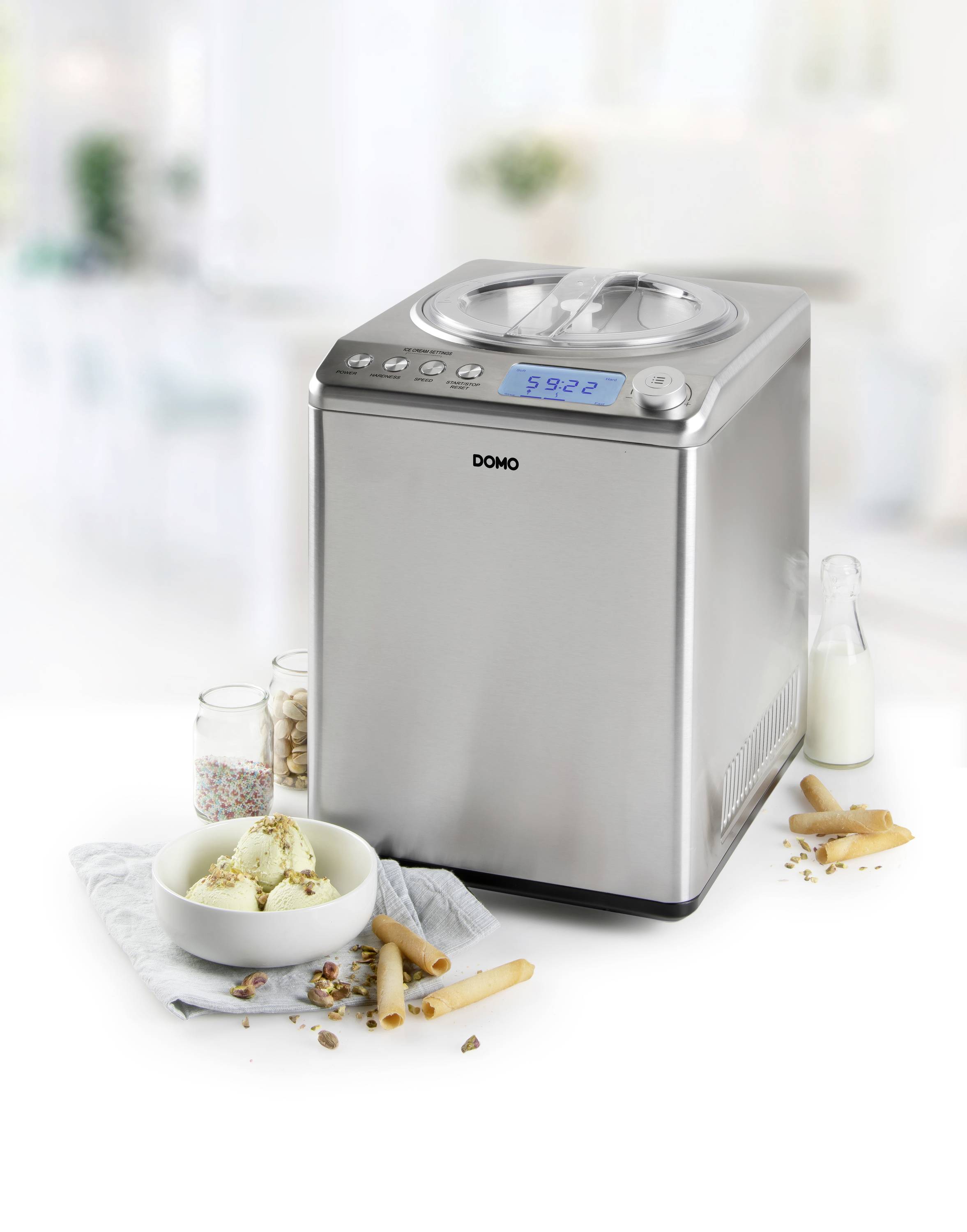 Machine à glace en acier inoxydable avec affichage numérique, entourée de gaufres, de crème glacée dans un bol et d'une bouteille de lait.