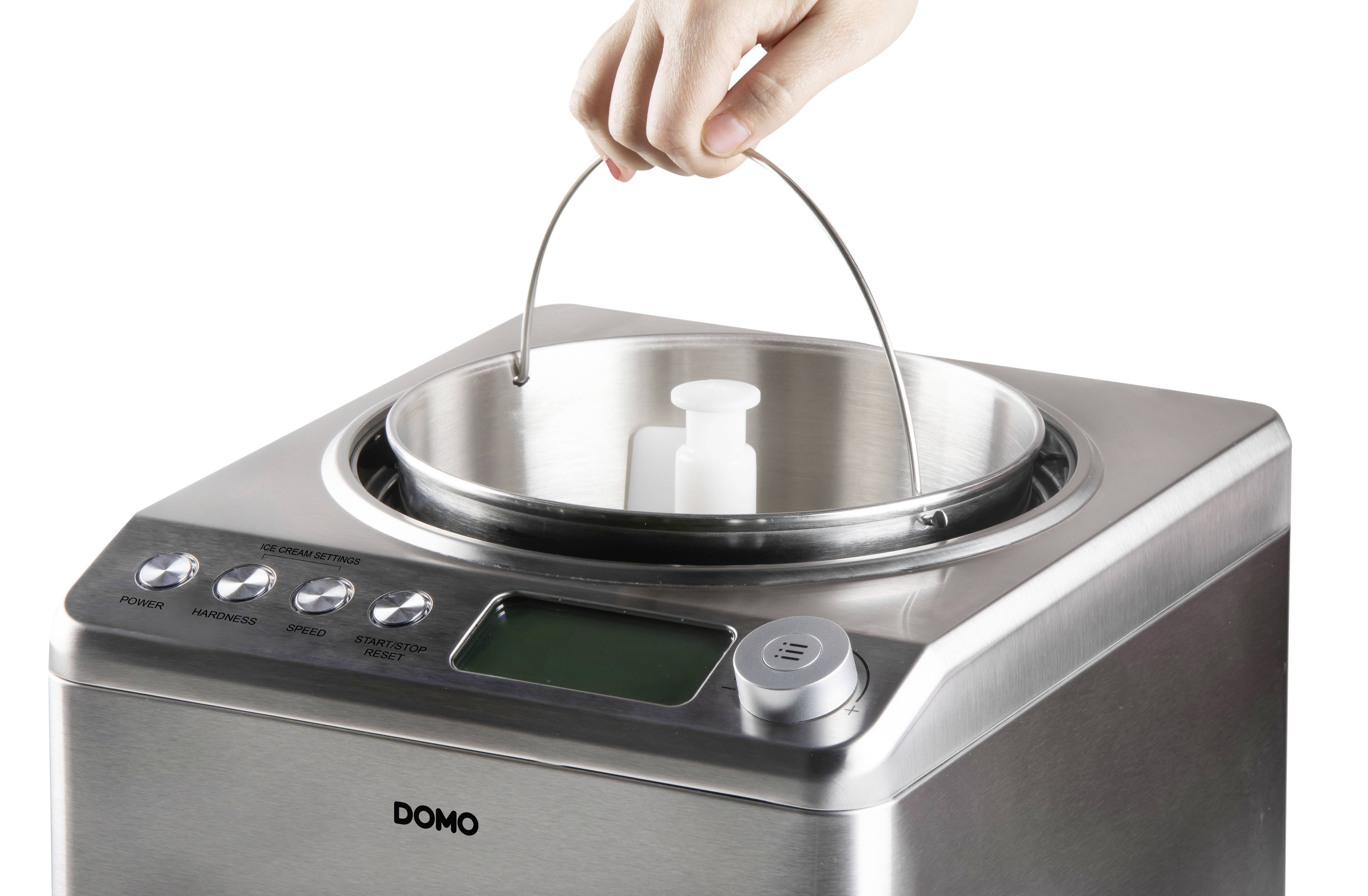 Une main soulève le couvercle d'une casserole en acier inoxydable sur un appareil de cuisine équipé de boutons et d'un écran.