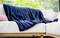 Un canapé confortable avec une couverture bleue et des coussins, placé devant une fenêtre offrant une vue sur des arbres verdoyants.