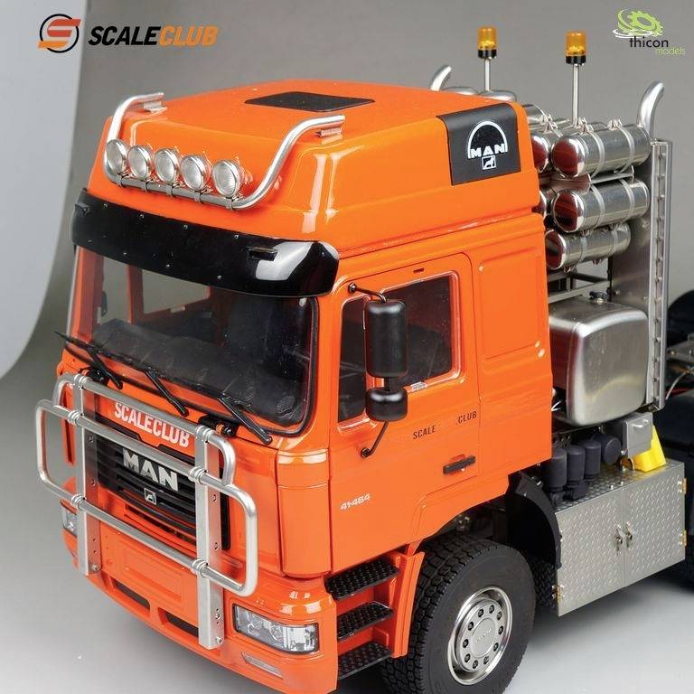 Un camion-modèle orange de MAN avec plusieurs réservoirs sur la surface de chargement. Des lumières orange sont situées au-dessus de la cabine du conducteur.