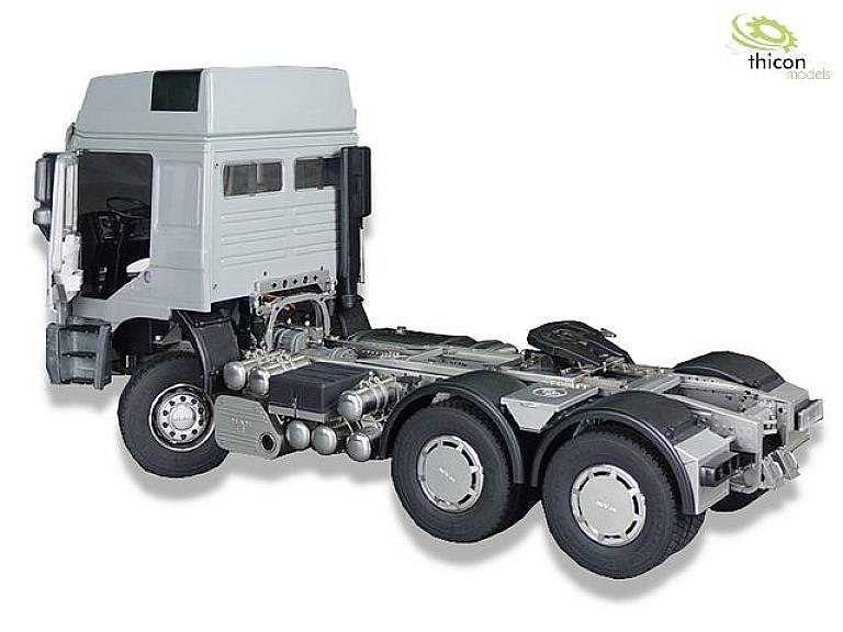 Un modèle d'un camion argenté sans remorque est représenté, visible de côté, sur une surface blanche.