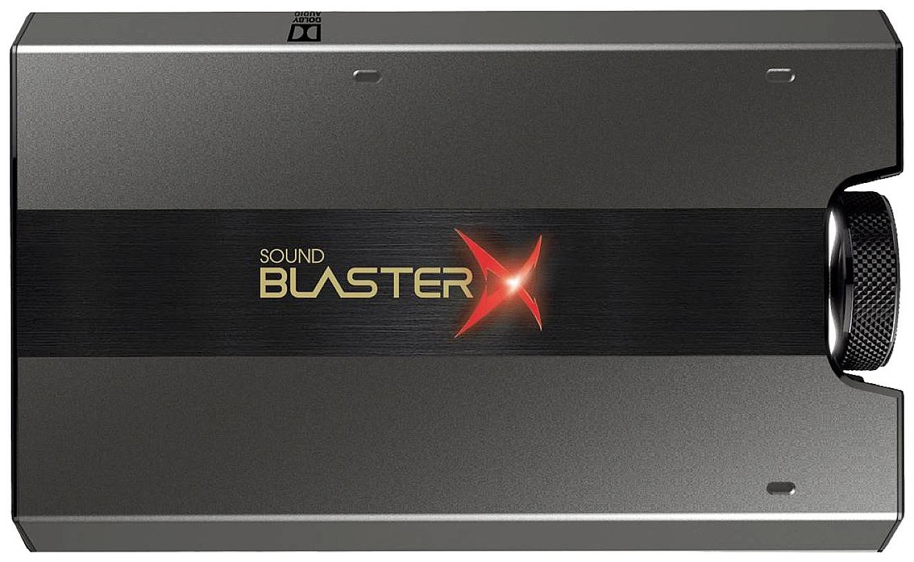 Une carte son externe noire portant l'inscription 'Sound Blaster X' au centre. Elle présente un design compact et rectangulaire.