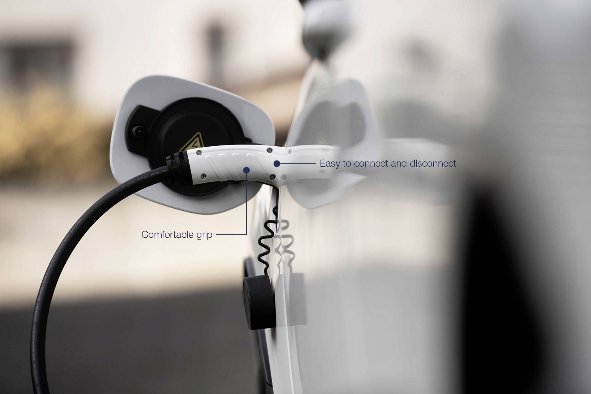 Un câble de charge est connecté à un véhicule électrique. Il présente des remarques sur la préhension ergonomique et la facilité de connexion.