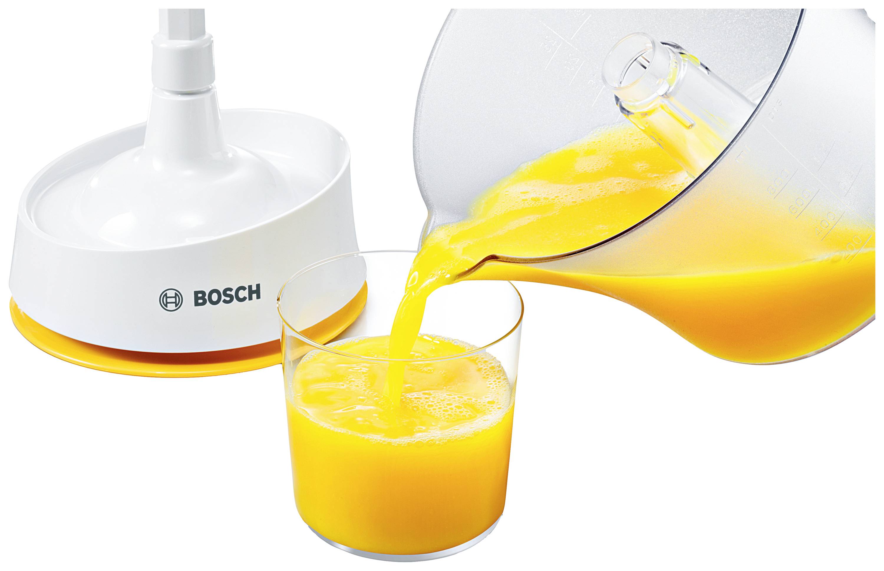 Une machine de cuisine verse du jus d'orange fraîchement pressé dans un verre. Un élément d'appareil Bosch est visible en arrière-plan.