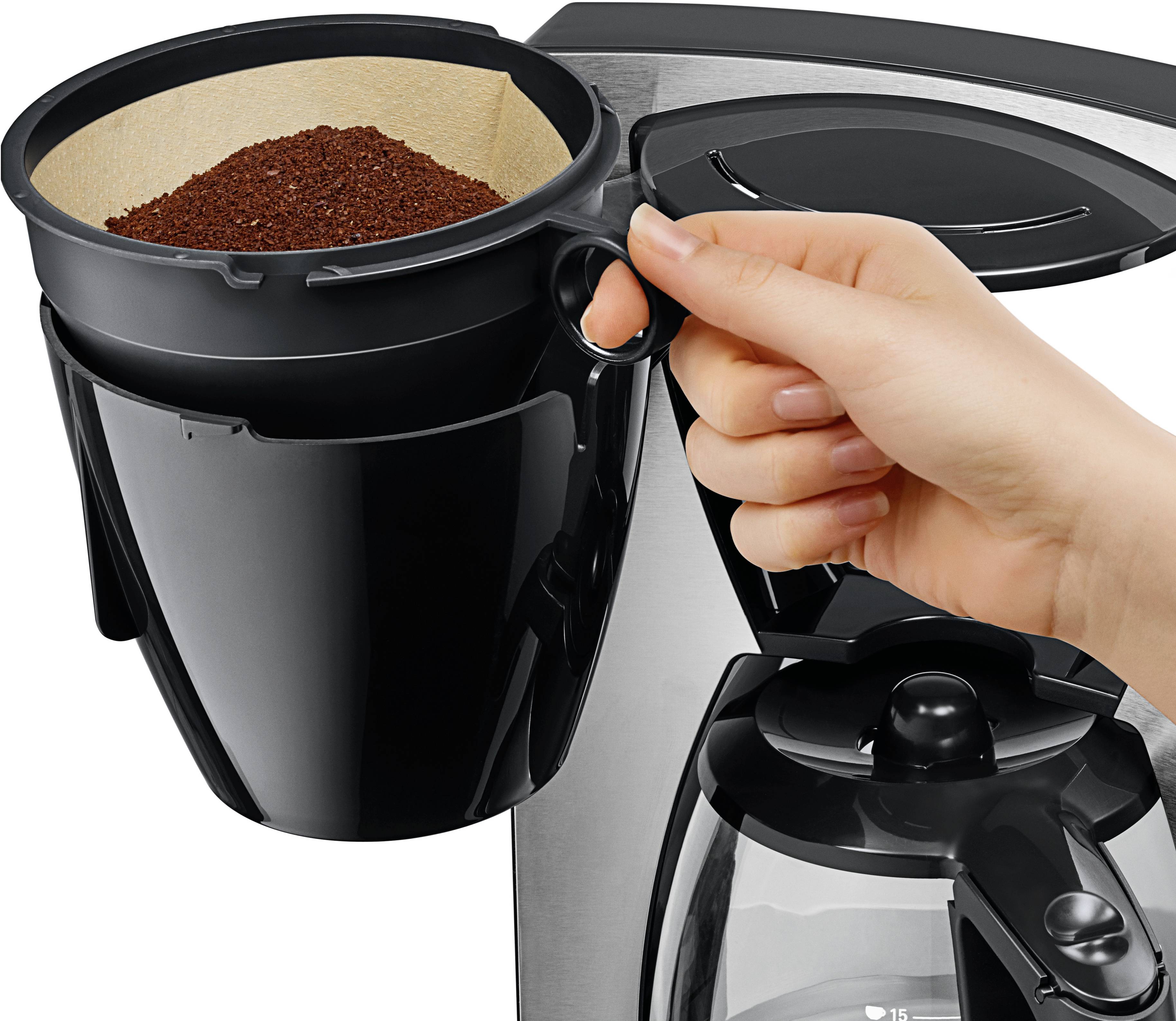 Une main place le porte-filtre à café rempli de café moulu frais dans une machine à café.