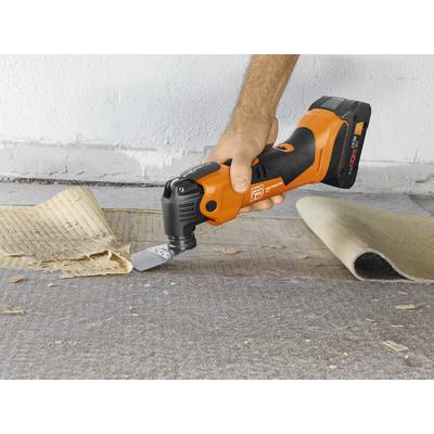 Une personne utilise un outil électrique orange pour enlever des restes de moquette d'un sol. L'outil est un appareil multifonction équipé d'une lame à gratter.