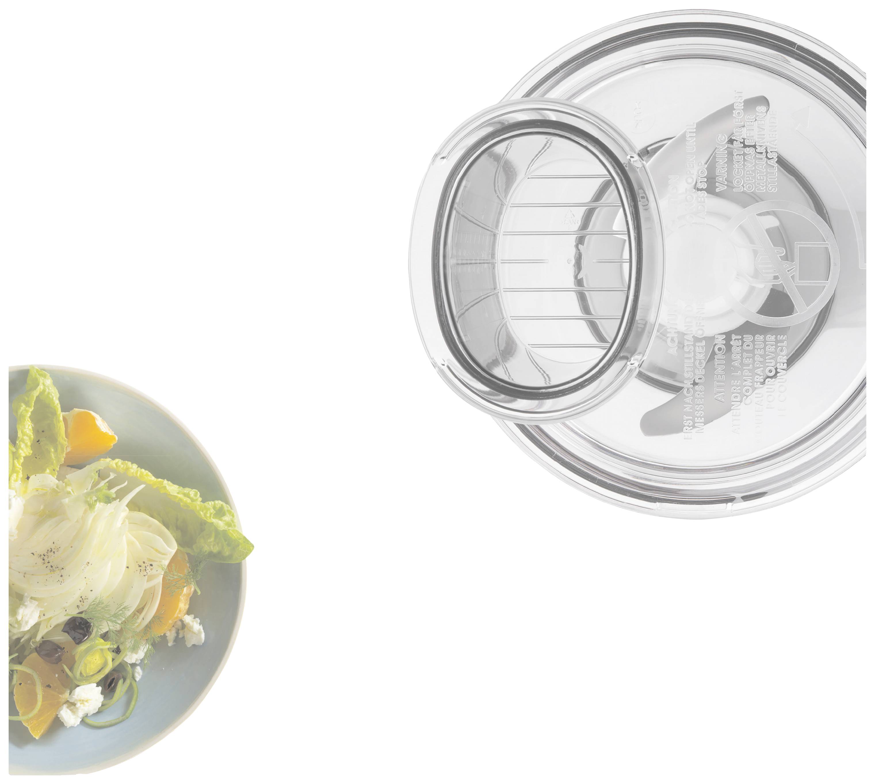 Une assiette de salade fraîche et un couvercle transparent en plastique d'un robot de cuisine avec ouverture de remplissage sur la droite.