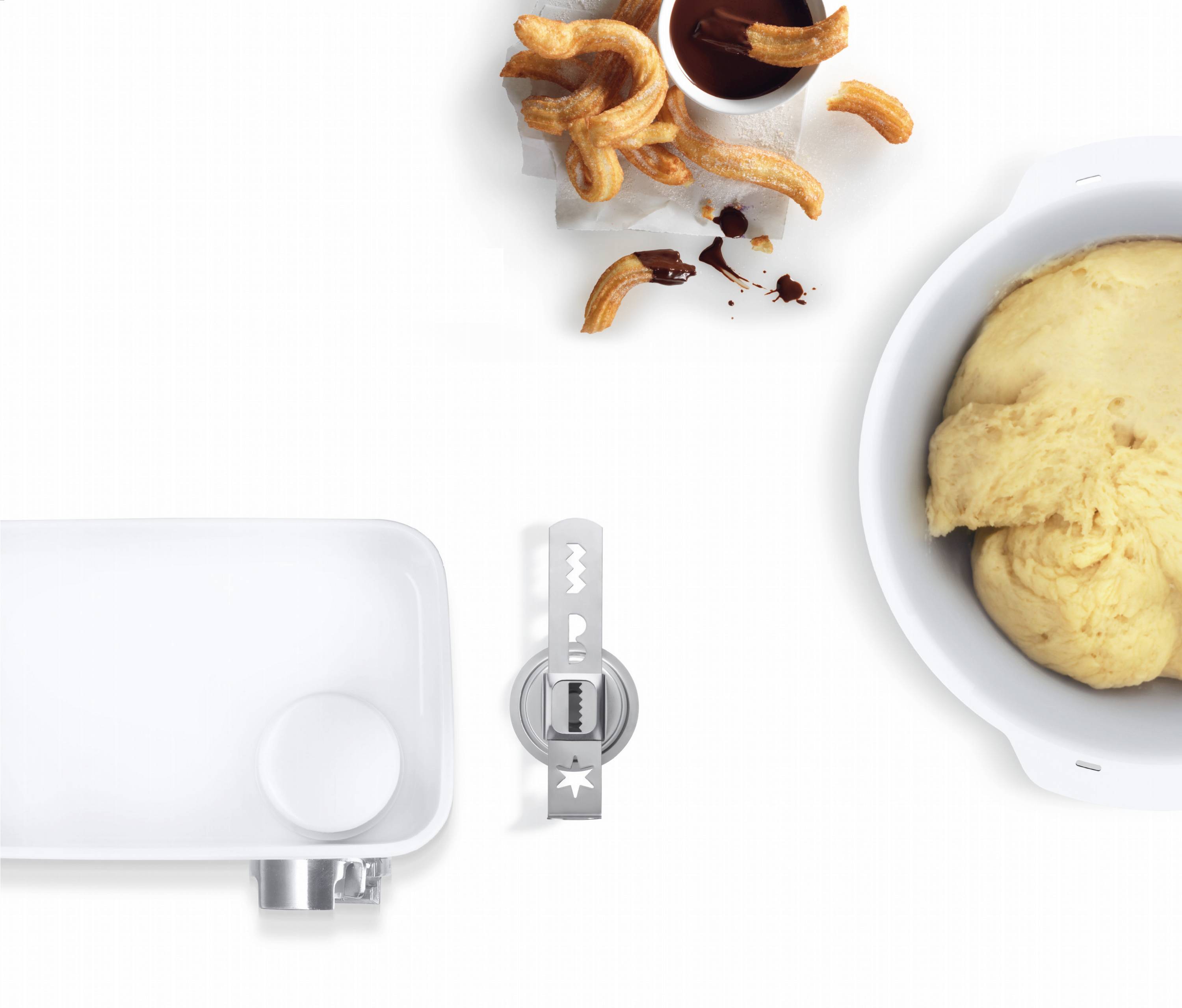 Pâte dans un bol, à côté des pâtisseries frites avec de la sauce au chocolat, à gauche un robot de cuisine.