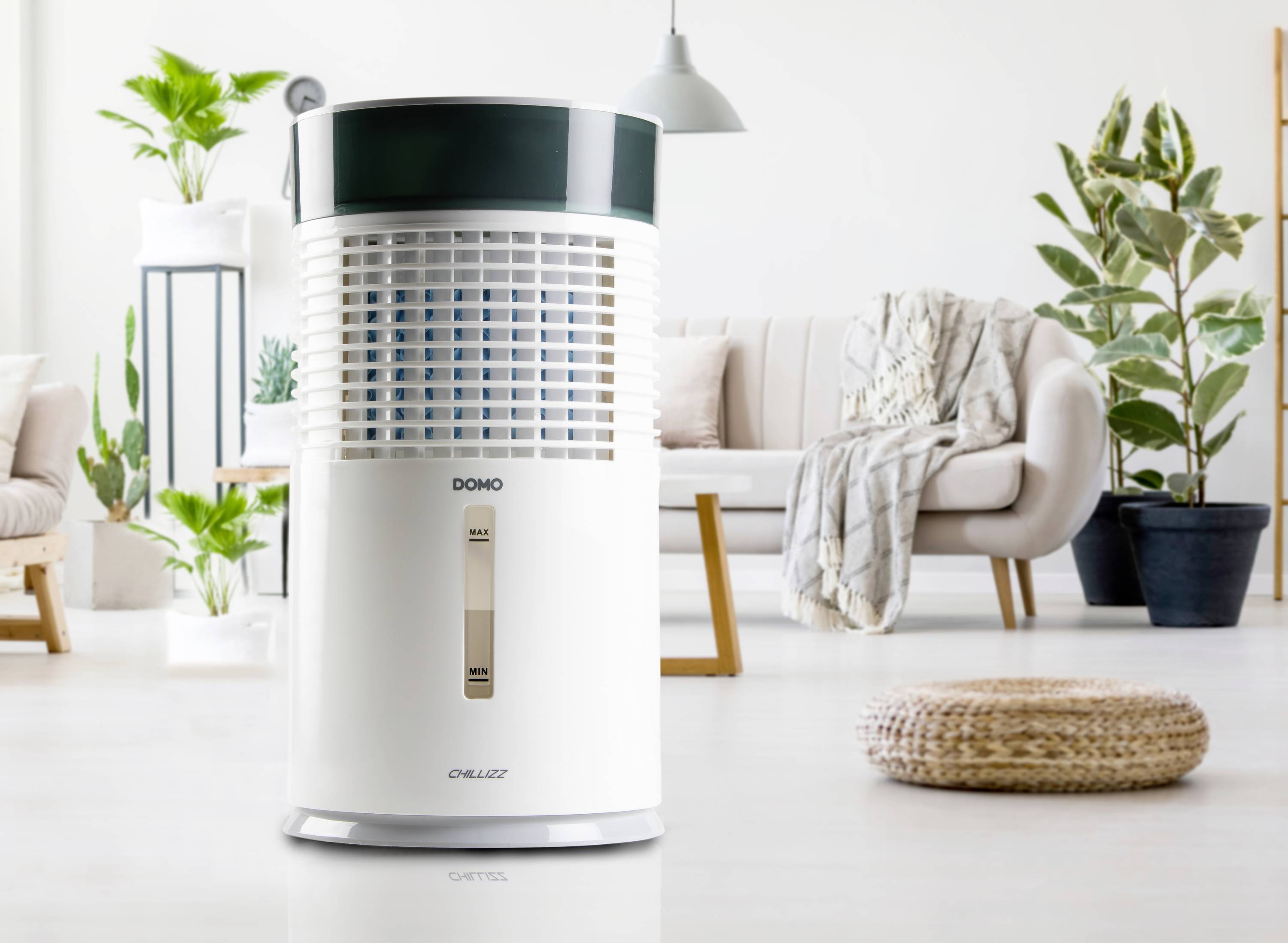 Un déshumidificateur est placé dans un salon aménagé de manière moderne, à côté de plantes et d'un canapé.