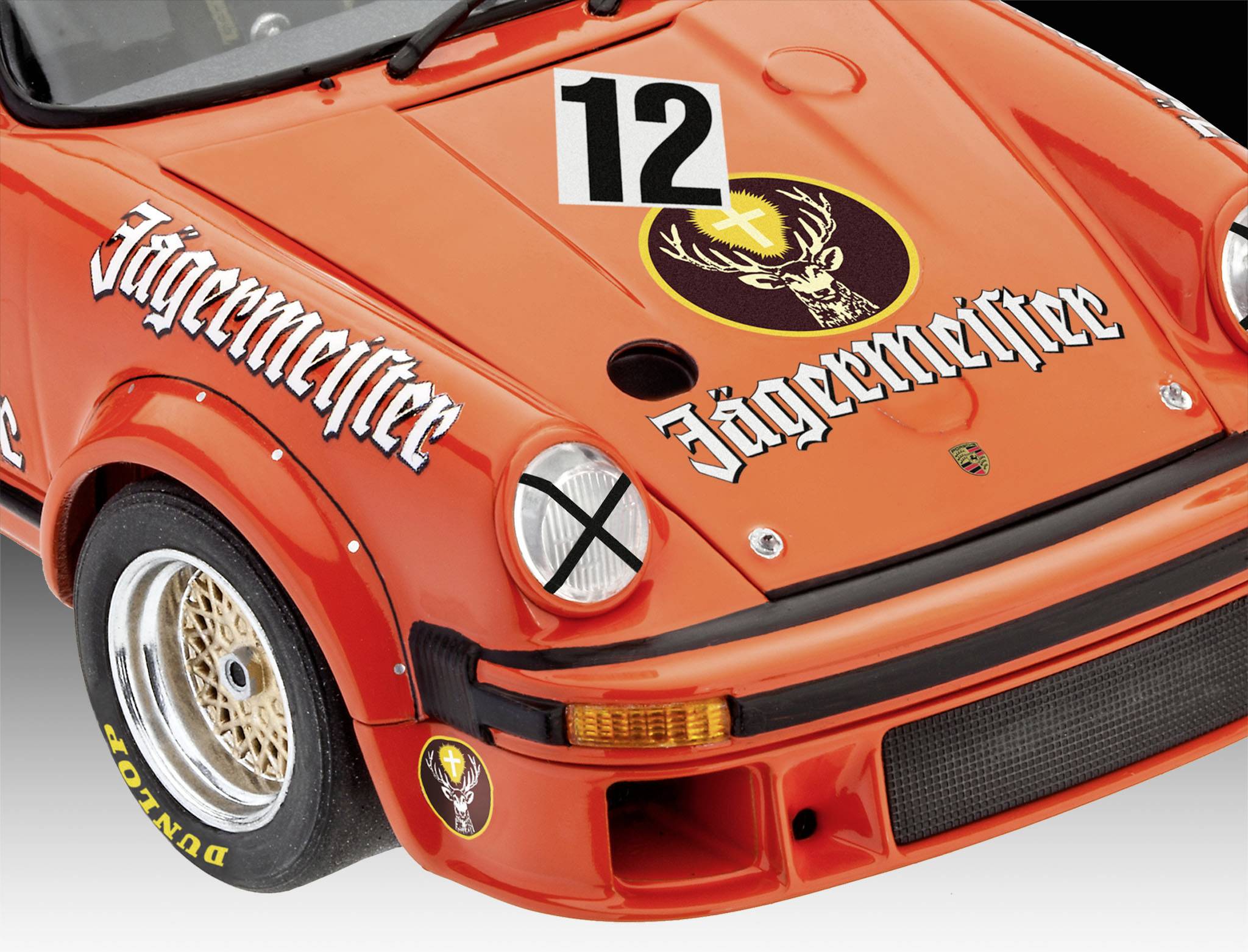 Voiture miniature rouge portant l'inscription 'Jägermeister' et le numéro 12 sur le capot. La décoration de course et les pneus de course sont visibles.