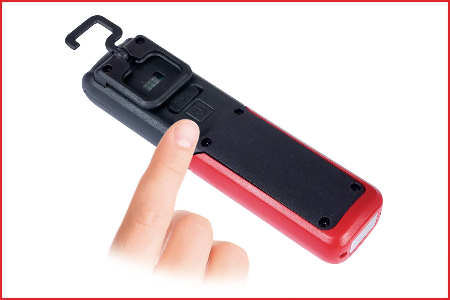 Une main appuie sur un bouton noir d'un dispositif rouge et noir avec un crochet en haut.