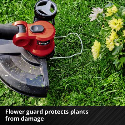 Un coupe-bordure avec protection 'Flowerguard' travaille dans un jardin, entouré d'herbe verte et de fleurs jaunes.