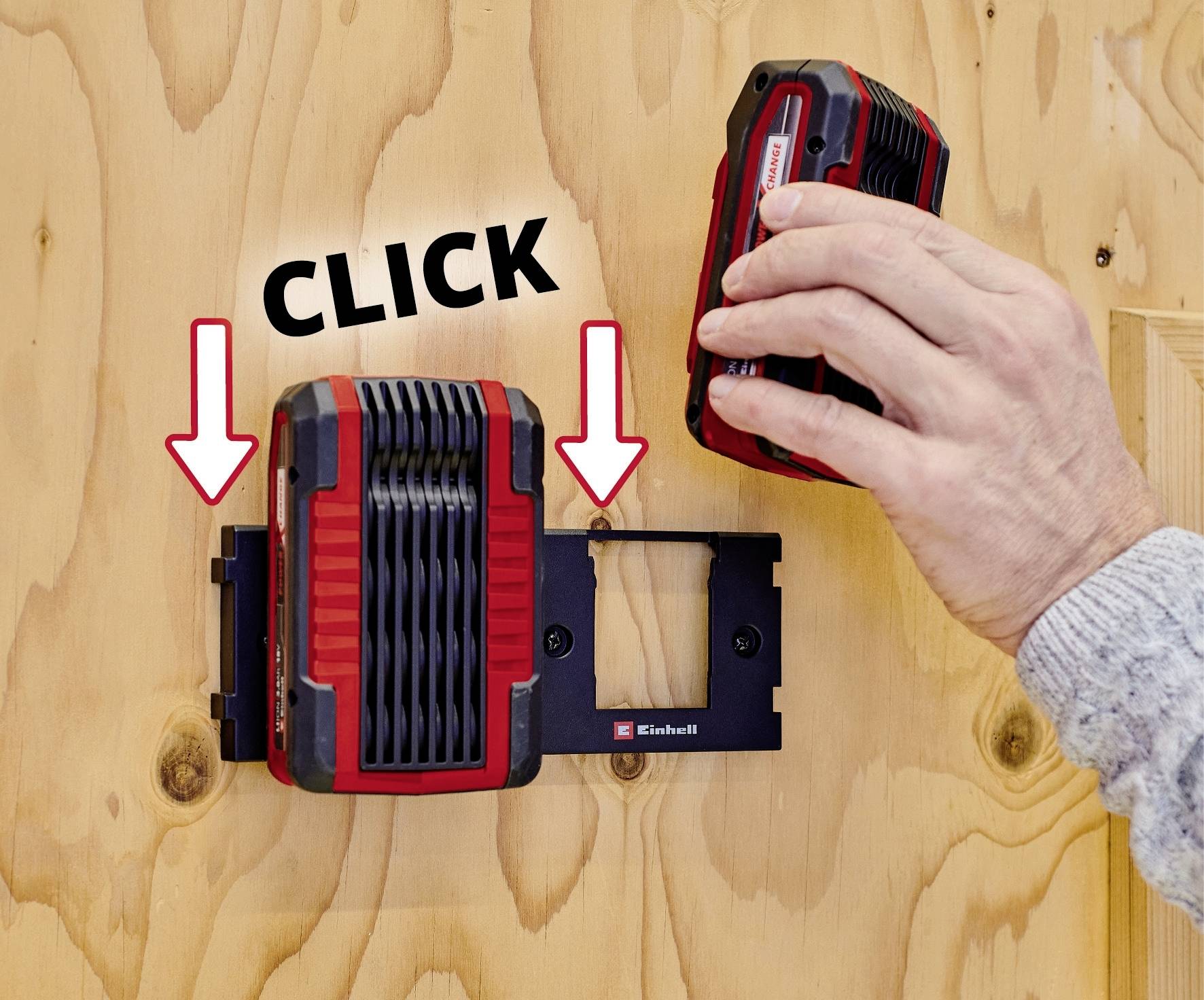 Une main insère une batterie rouge dans un chargeur mural. Deux flèches et le mot 'CLICK' indiquent le sens d'insertion.