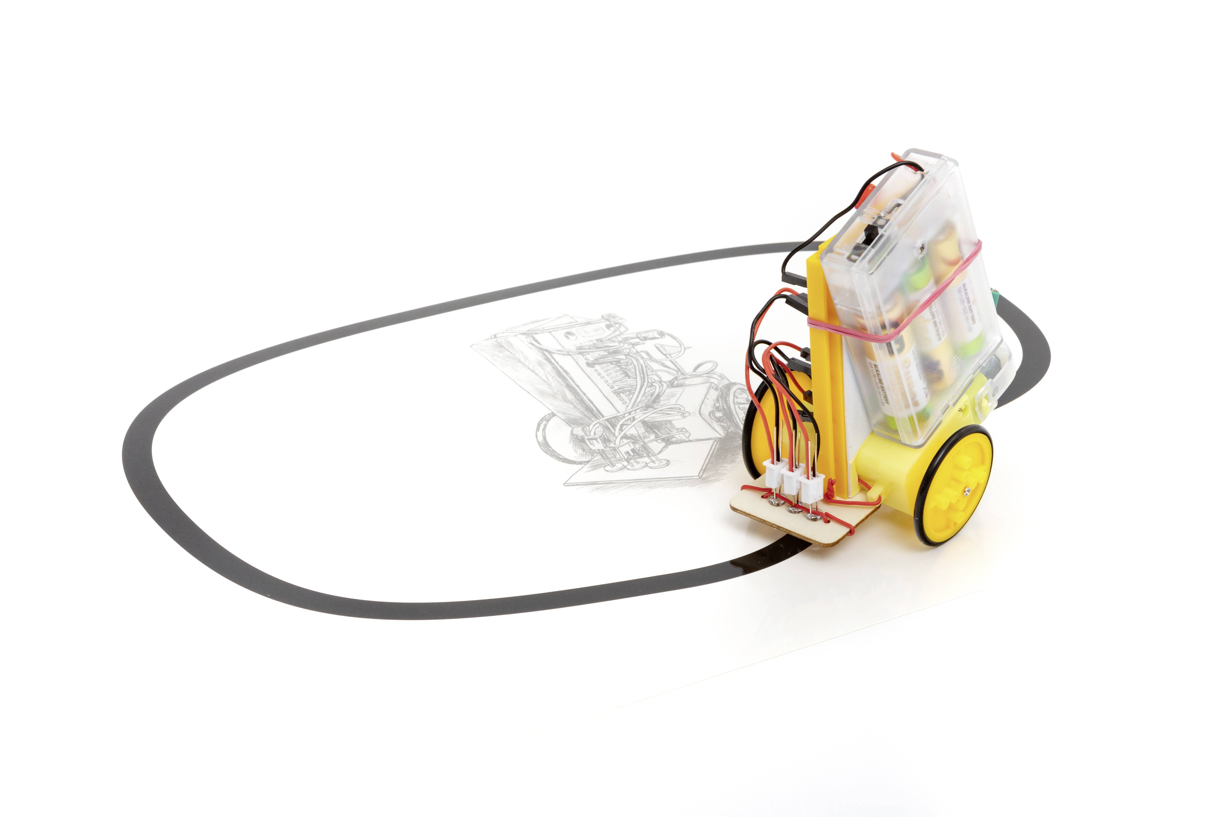 Un petit robot avec des roues jaunes suit une ligne noire sur une surface blanche. Des circuits sans fil et des batteries sont visibles.