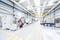 Un espace industriel lumineux et moderne avec un bras robotique orange, entouré de machines et de larges allées de production.